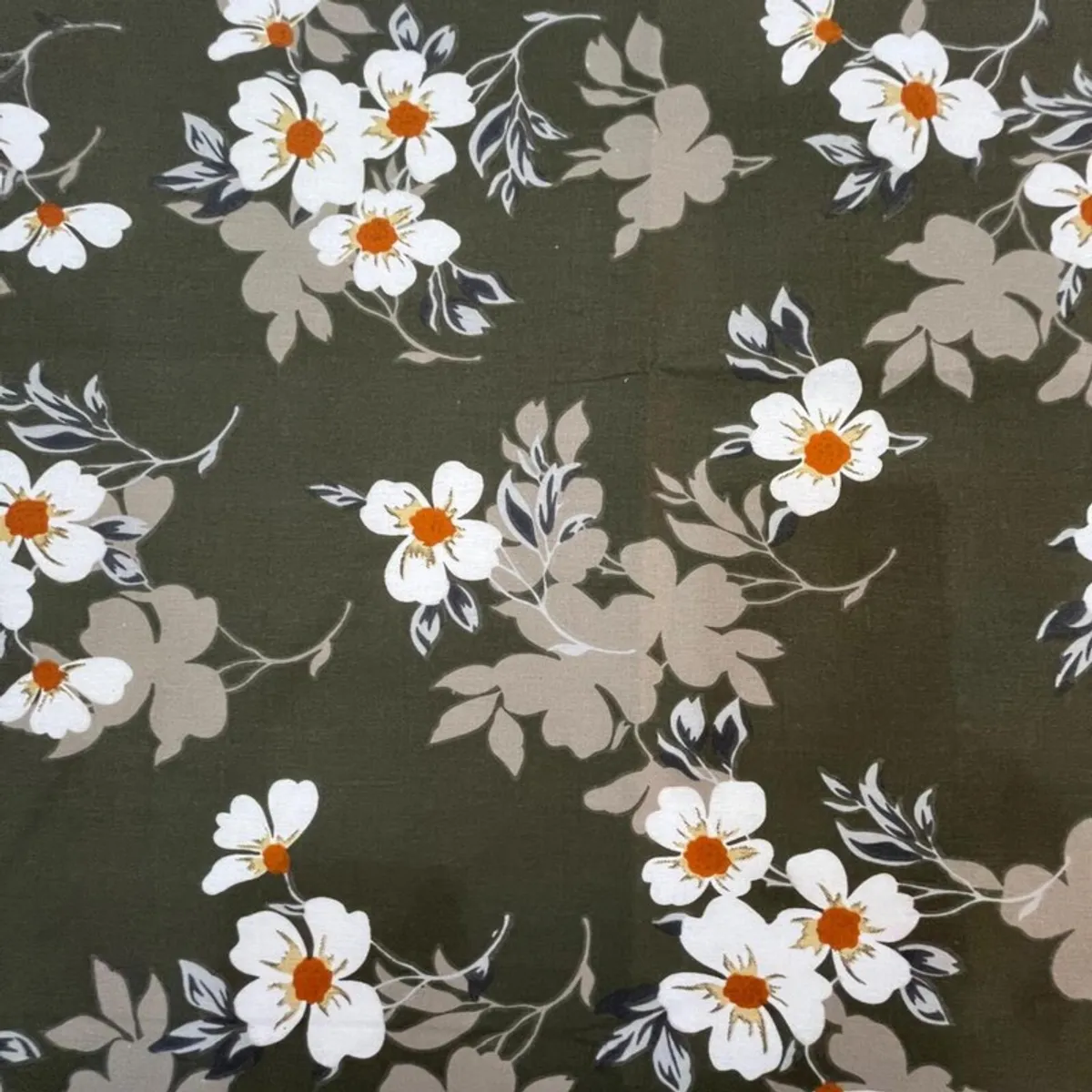 Detailed view of white and orange flowers on the green bedsheet