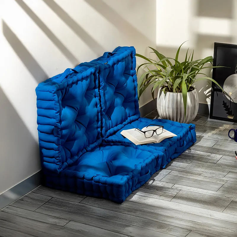Four classic blue floor cushions arranged as low floor seating against a wall