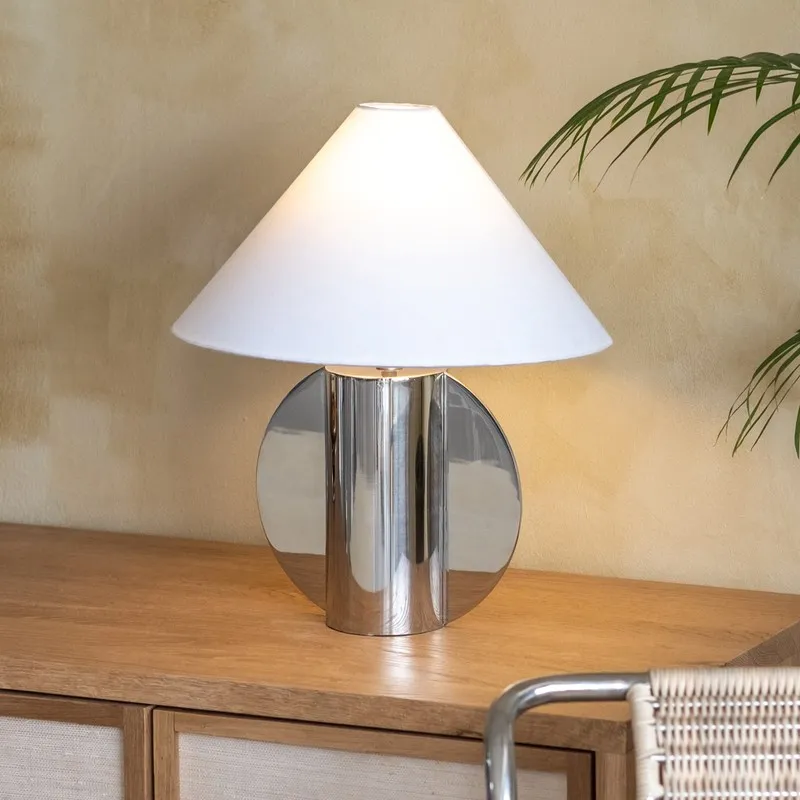 Modern silver table lamp with wide white shade on a console table