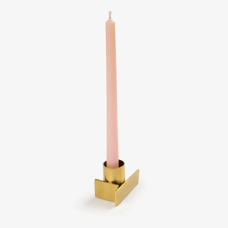 Gold geometric candle holder holding a tall pink taper candle