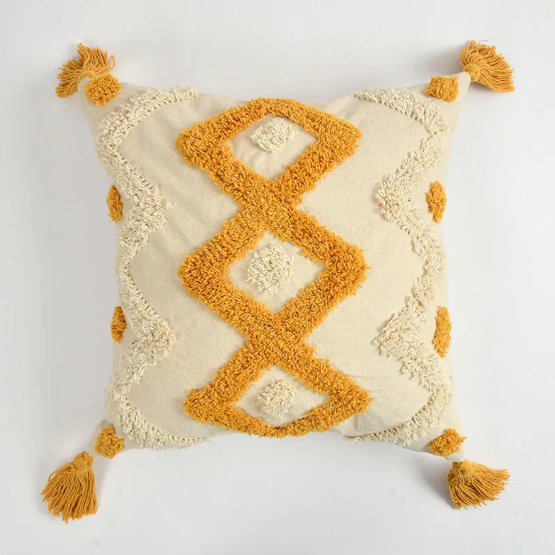 Front view of a cream cushion cover with mustard geometric tufting and tassel corners