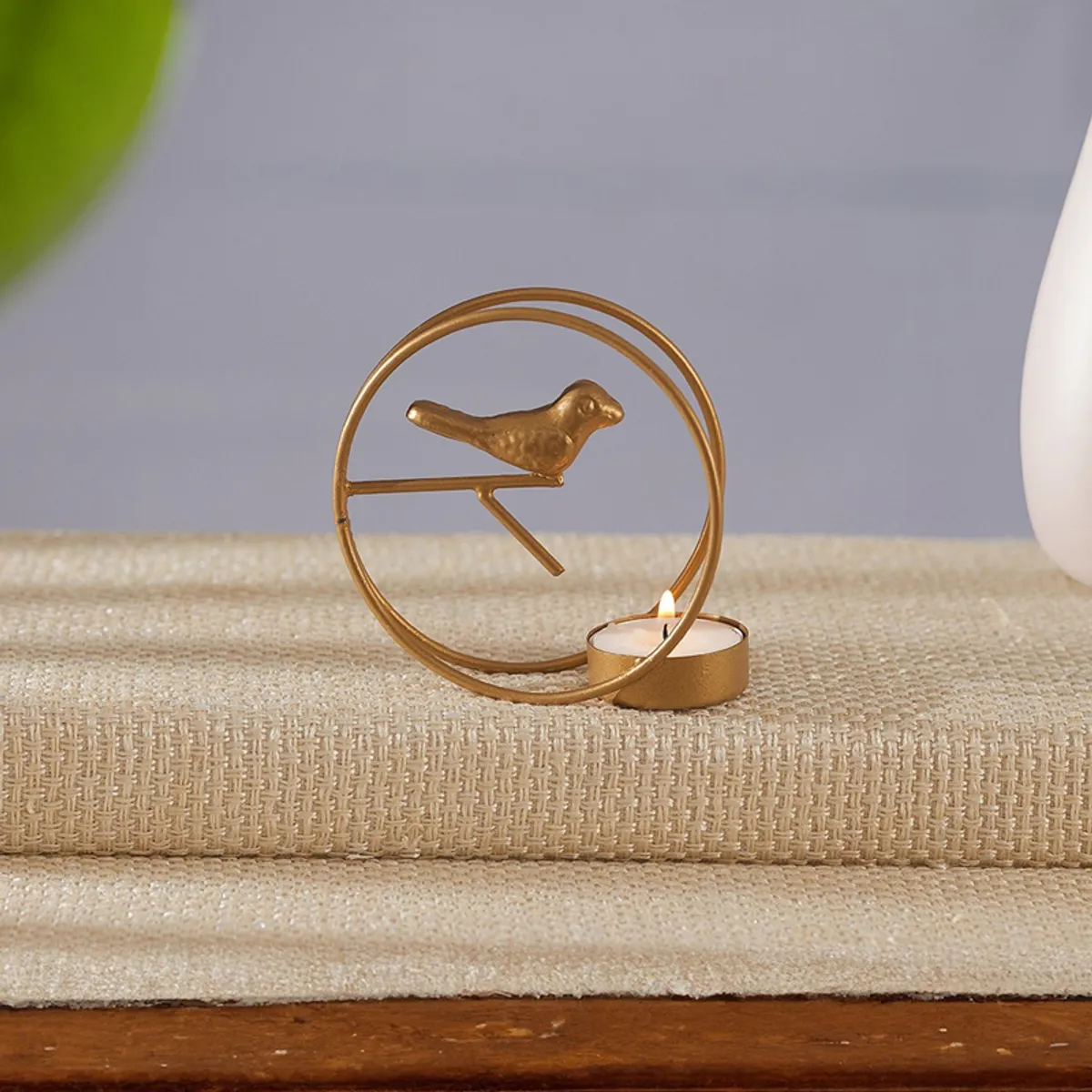 Close-up of a gold bird-shaped tealight holder with circular frame