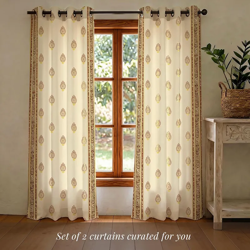 Pair of eyelet curtains with buta print and border hanging over a window.