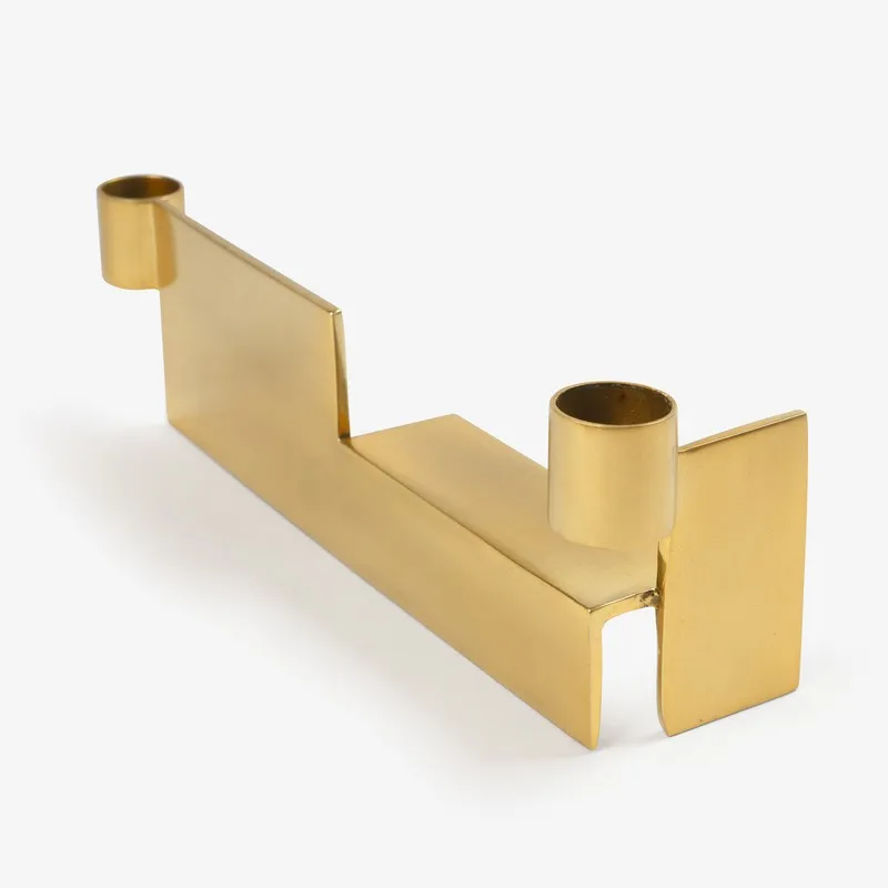 Angled view of a gold dual candle holder with geometric silhouette