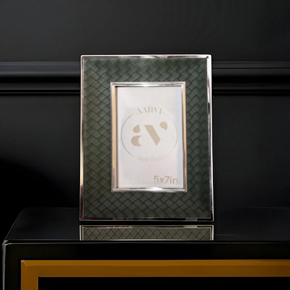Green leather-look photo frame with silver border on a black console