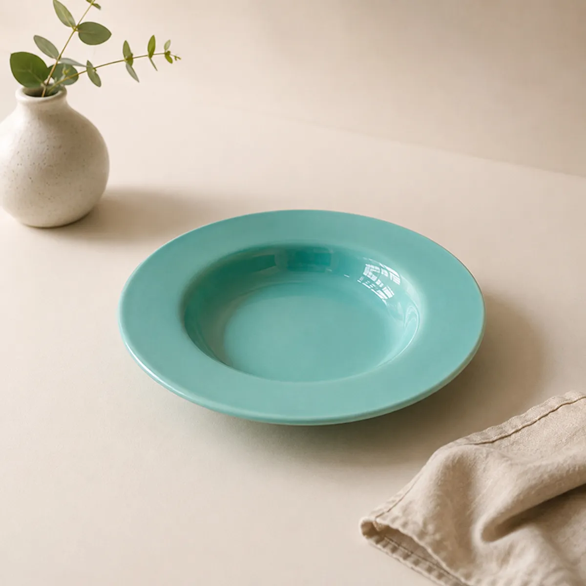 Single glossy teal pasta plate on a dining table