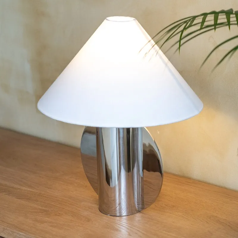 Close view of a polished silver table lamp with white tapered shade