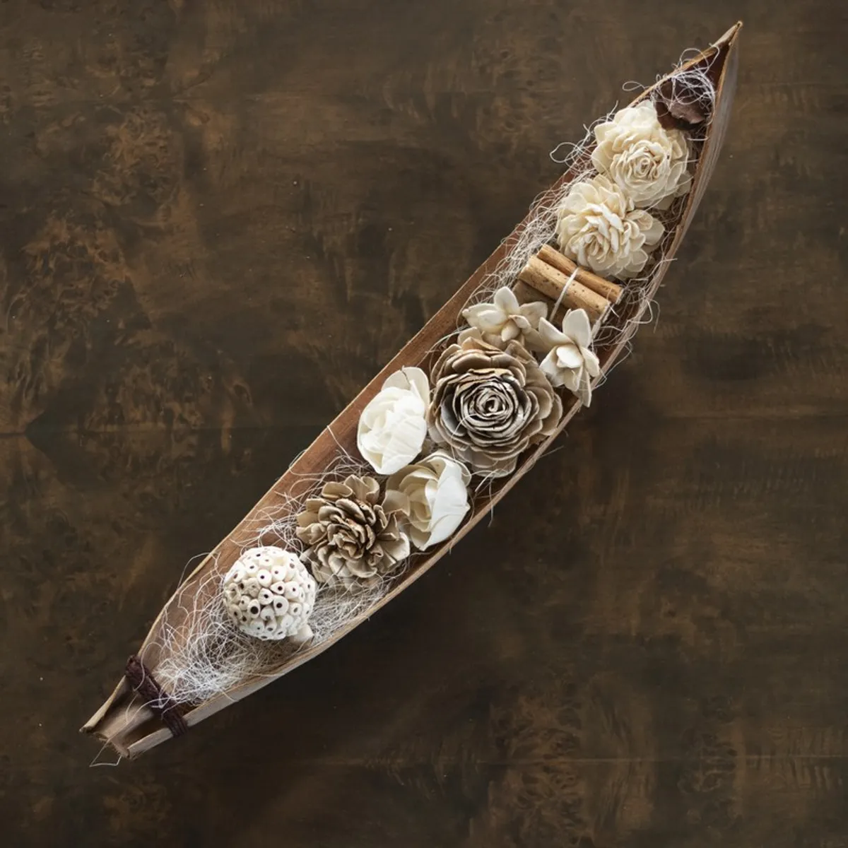 Top view of a brown and off-white floral arrangement in an elongated wicker base