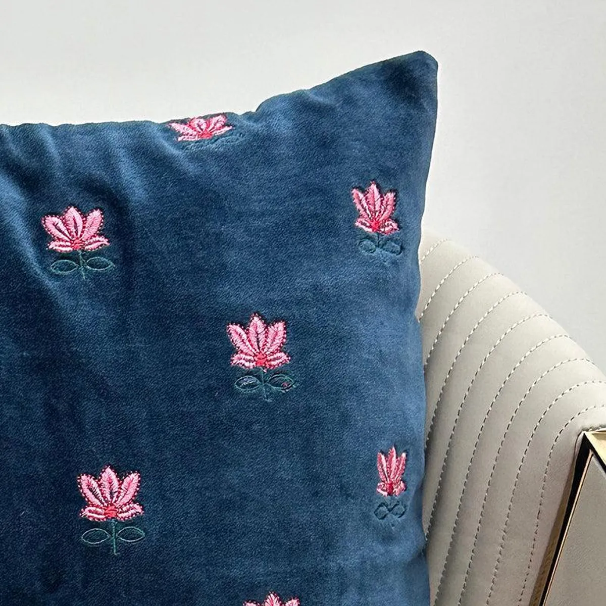 Close-up of blue cushion cover with pink embroidered floral motifs