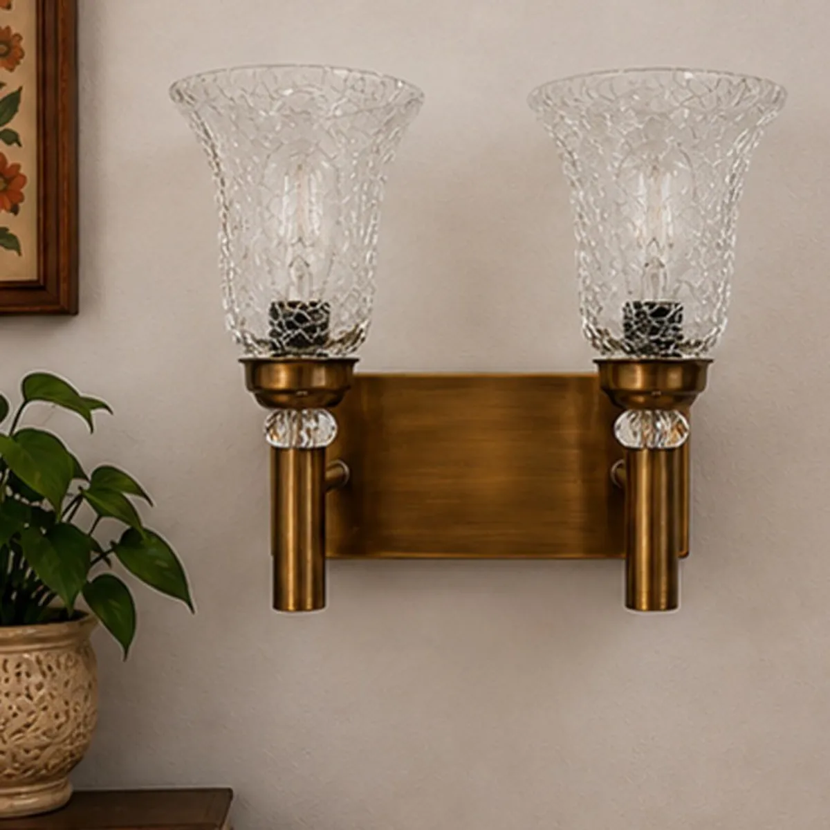 Gold twin glass wall lamp mounted against a light wall