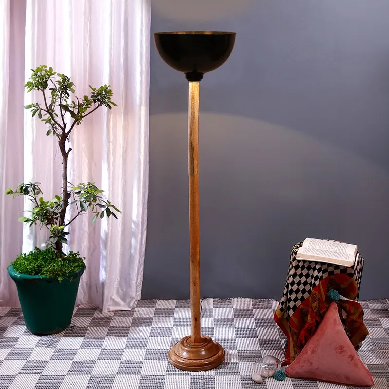 Wooden floor lamp with black uplight shade in a styled indoor setting