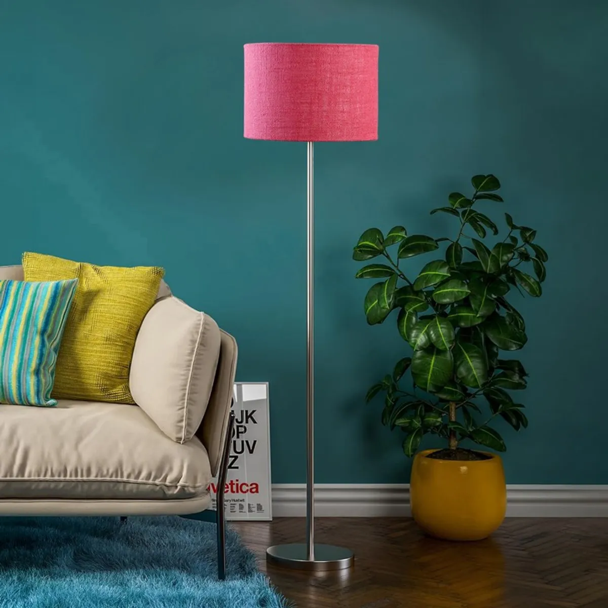 Pink drum-shade floor lamp with slim steel stand in a teal living room setting