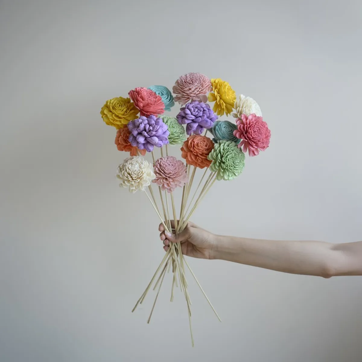 Hand holding a multicolour bouquet of sola wood flower sticks