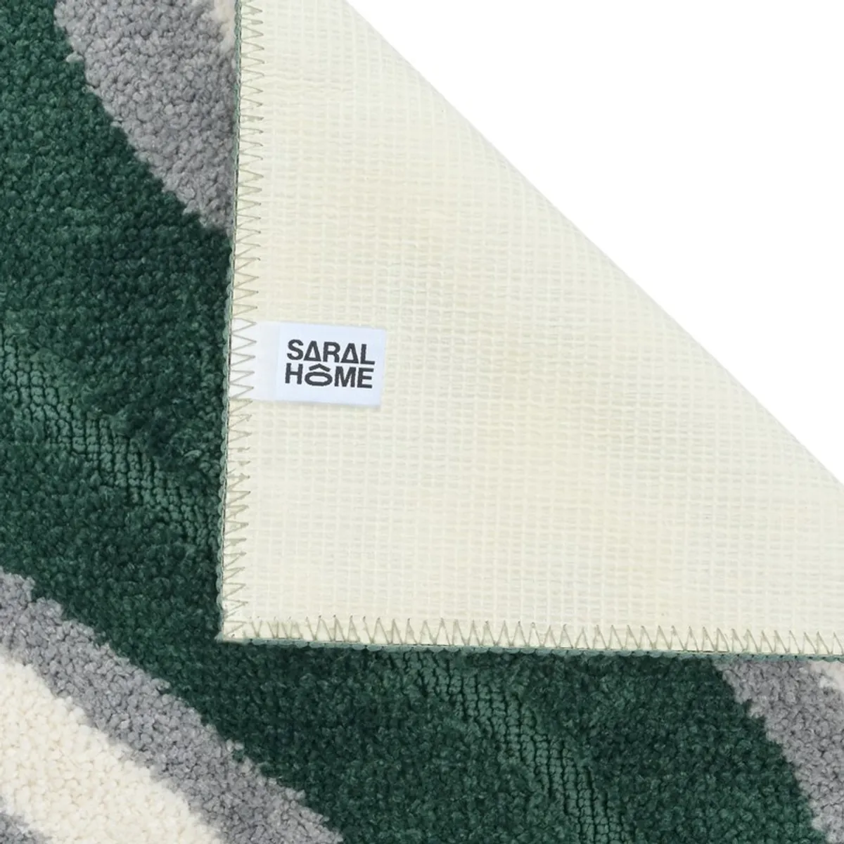 Corner of the bath mat showing its pale anti-skid backing and stitched edge