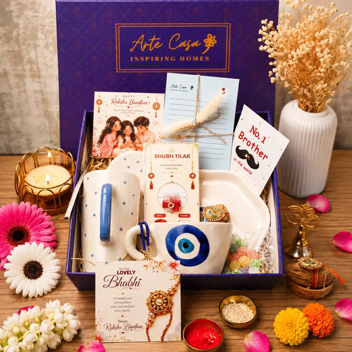 Open blue Raksha Bandhan hamper with mug, tumbler, cards, rakhi, sweets and gift box.