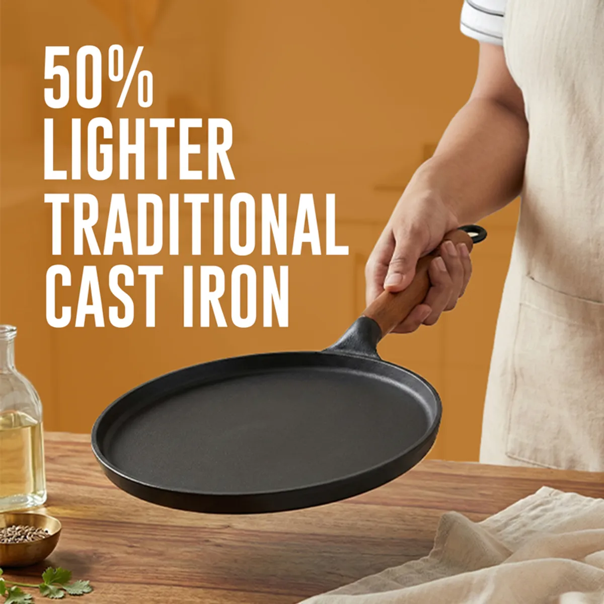 Black cast iron dosa tawa shown being held by its wooden handle