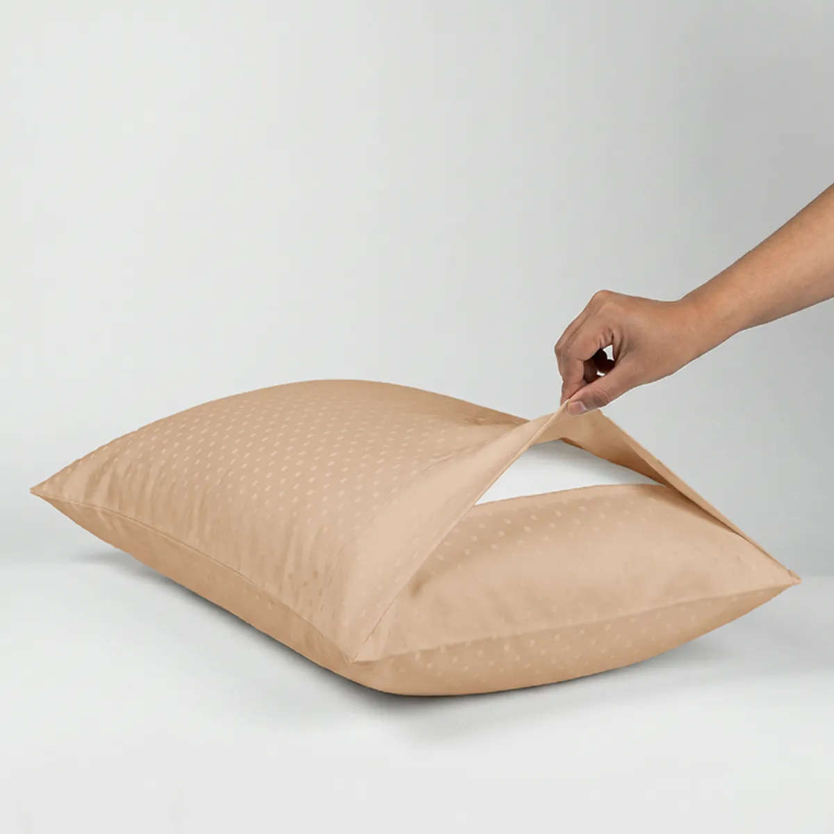 Almond pillow cover shown being placed over a pillow