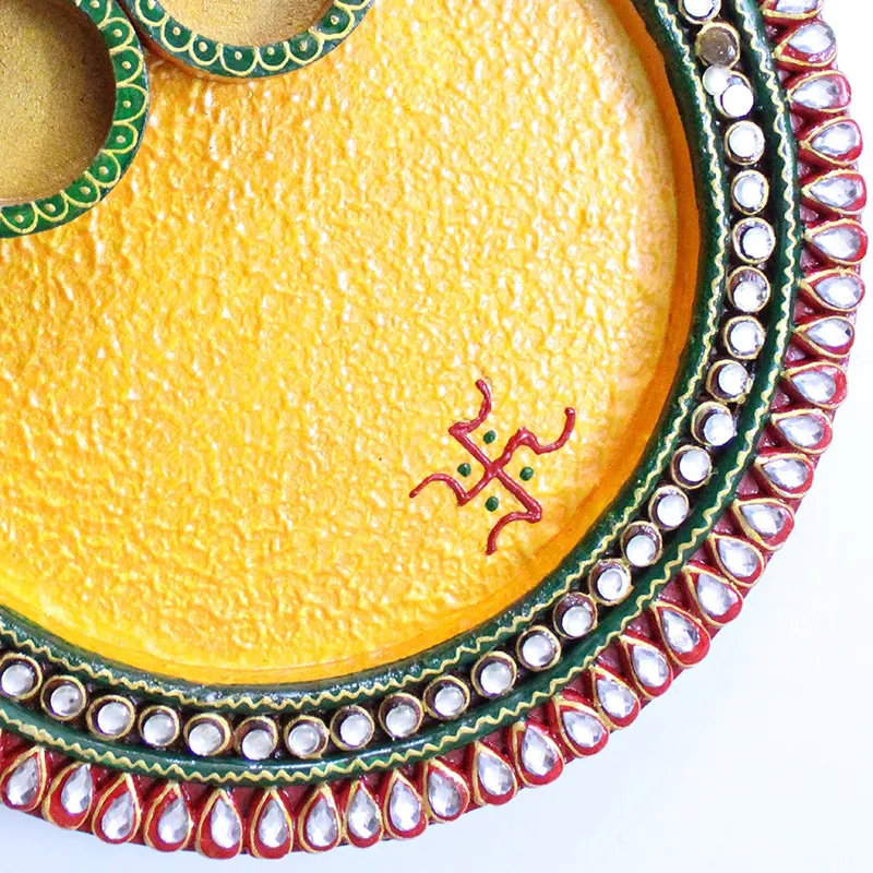 Close-up of the textured yellow thali surface and embellished rim detail