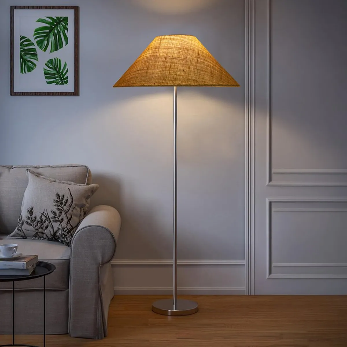 Yellow jute floor lamp with warm glow beside a sofa in a neutral room