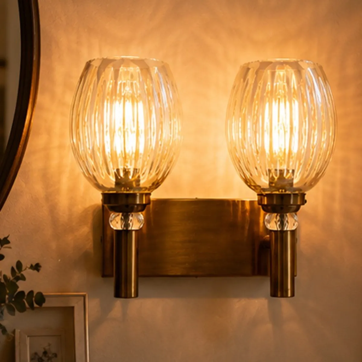 Close-up of two transparent ribbed glass globes on a gold wall lamp