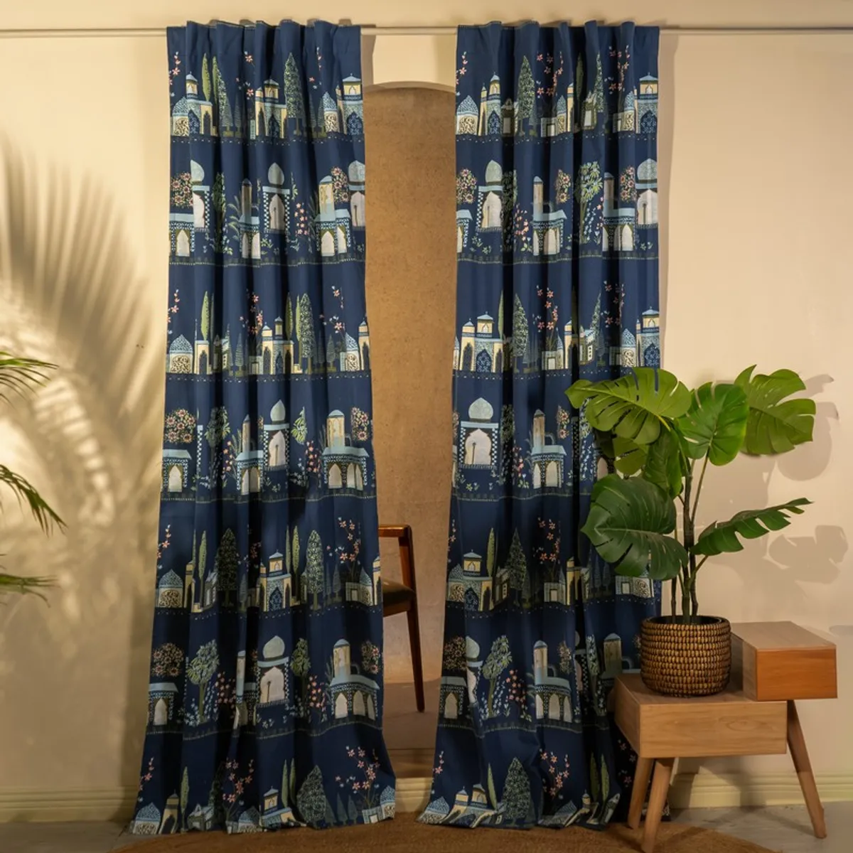 Pair of blue patterned curtains hanging from a rod in a bright room.