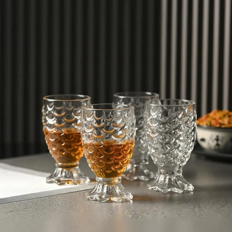 Four textured clear glasses, two filled with amber drink, on a tabletop