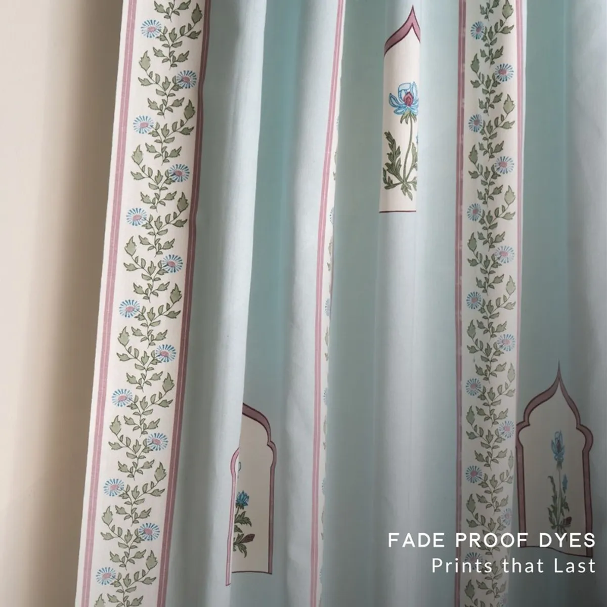 Close view of floral curtain borders and framed botanical motifs on light blue fabric.