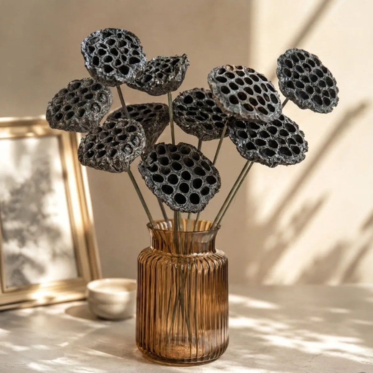 Black lotus seed pod sticks displayed in an amber ribbed vase