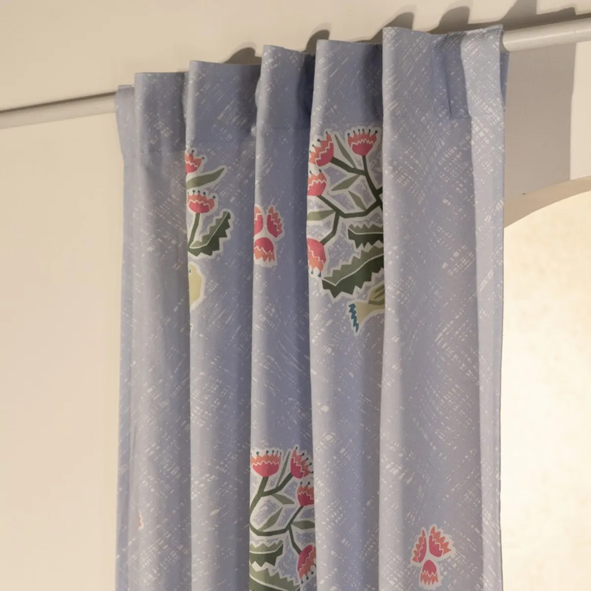 Back-tab light blue curtain with colourful floral print on a rod