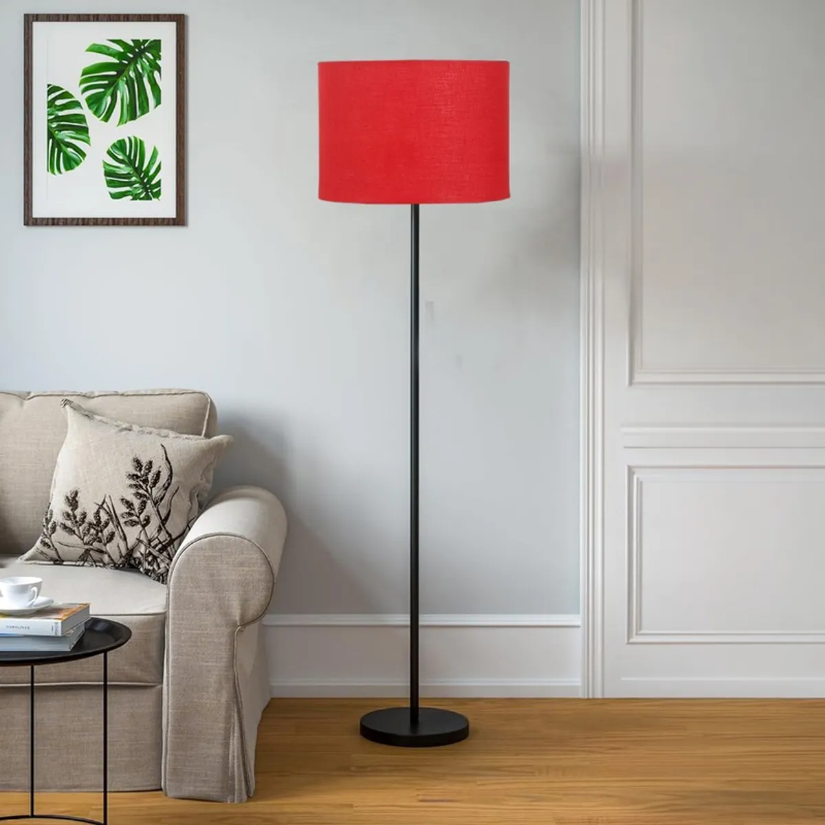 Red floor lamp with black stand placed beside a light sofa