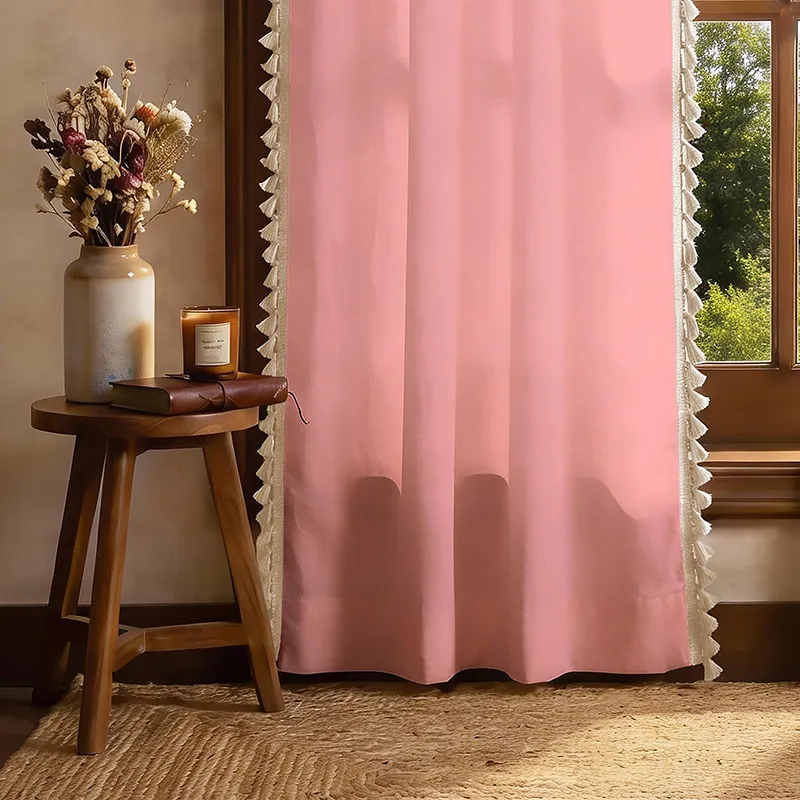 Lower section of a pink tasselled curtain beside a wooden side table