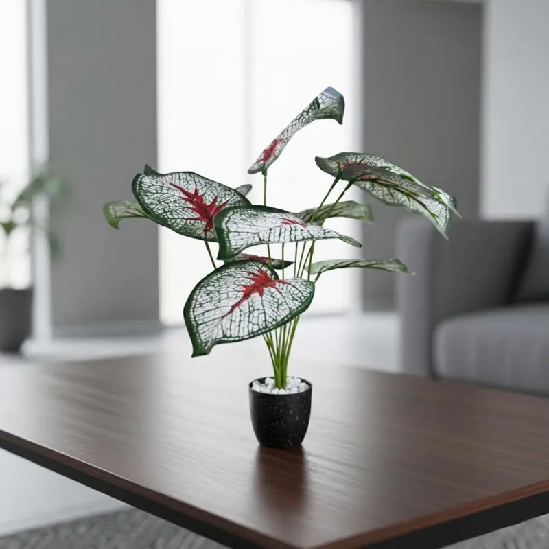 Single patterned-leaf artificial plant in a black pot on a dark tabletop