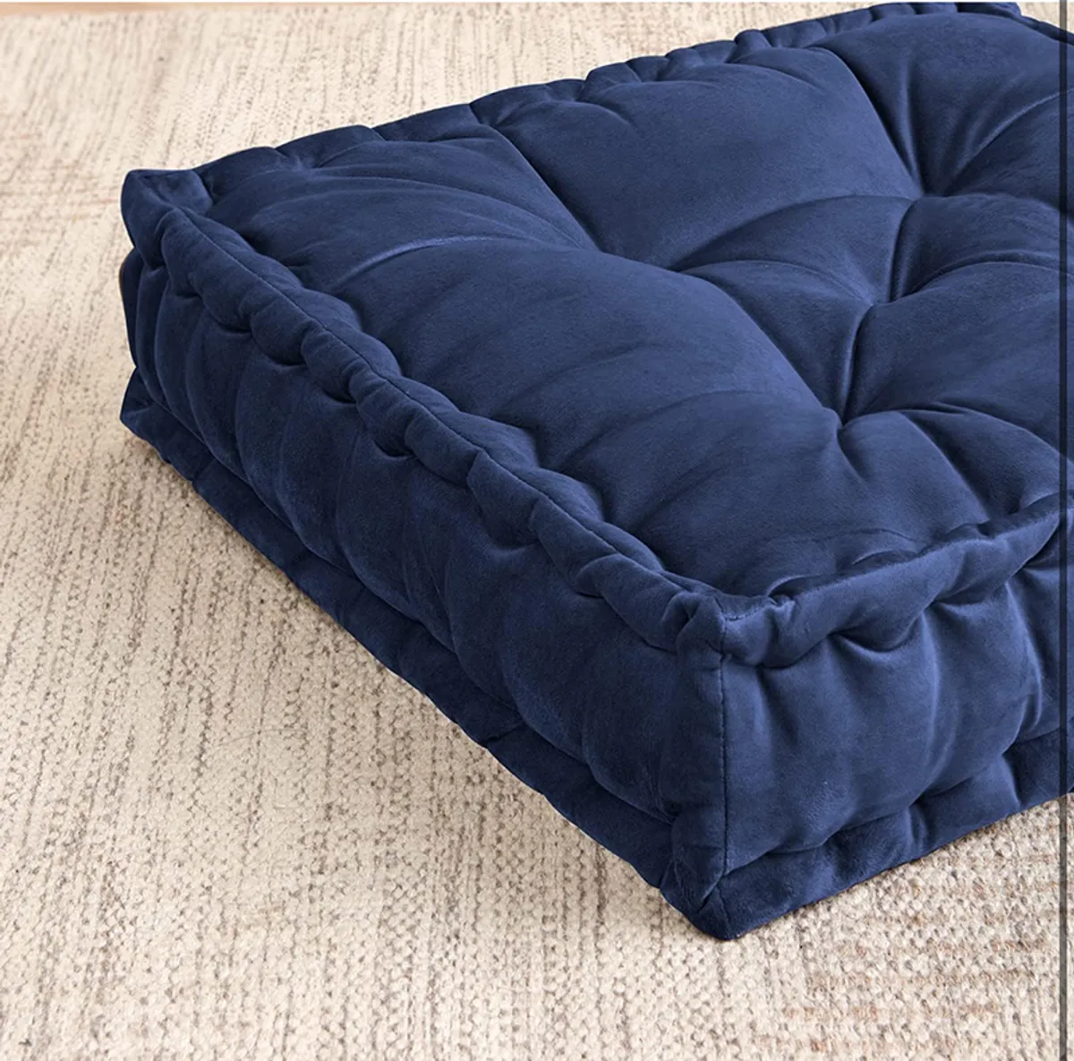 Close-up of the navy velvet tufted cushion surface and raised square shape