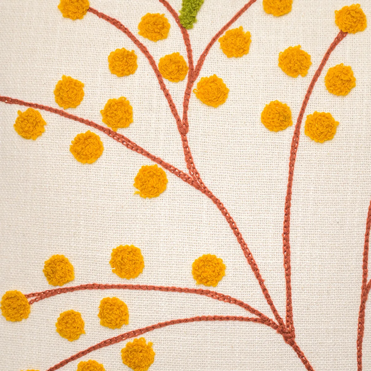Close-up of yellow floral embroidery on an ivory cushion cover