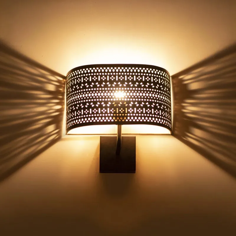 Close view of lit perforated wall lamp with warm glow and shadow pattern