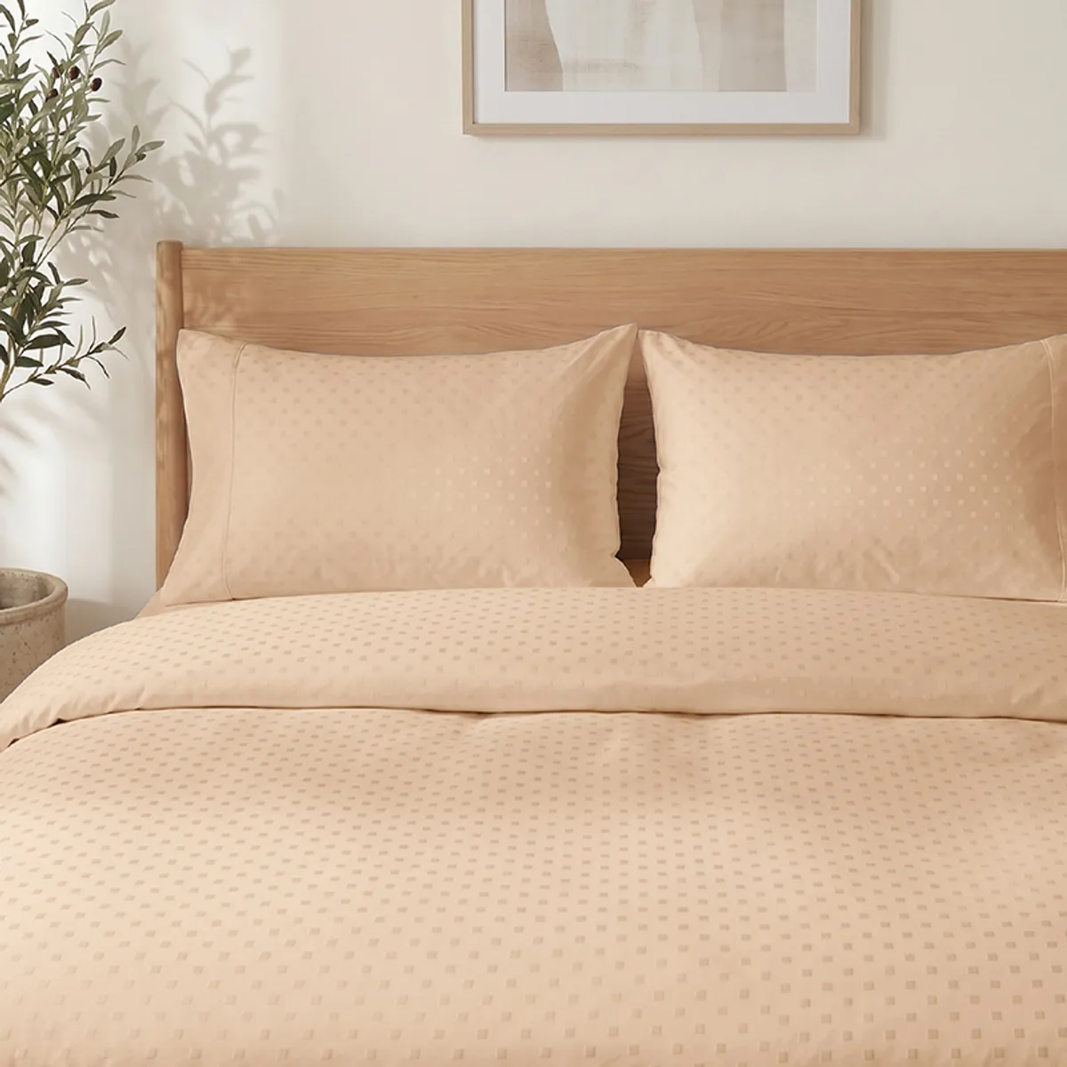 Two almond pillow covers with subtle geometric dots on a neatly made bed