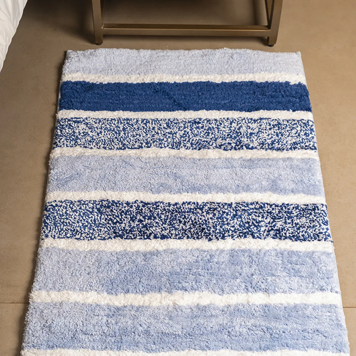 Close view of the blue and pastel striped plush runner beside a bedside table