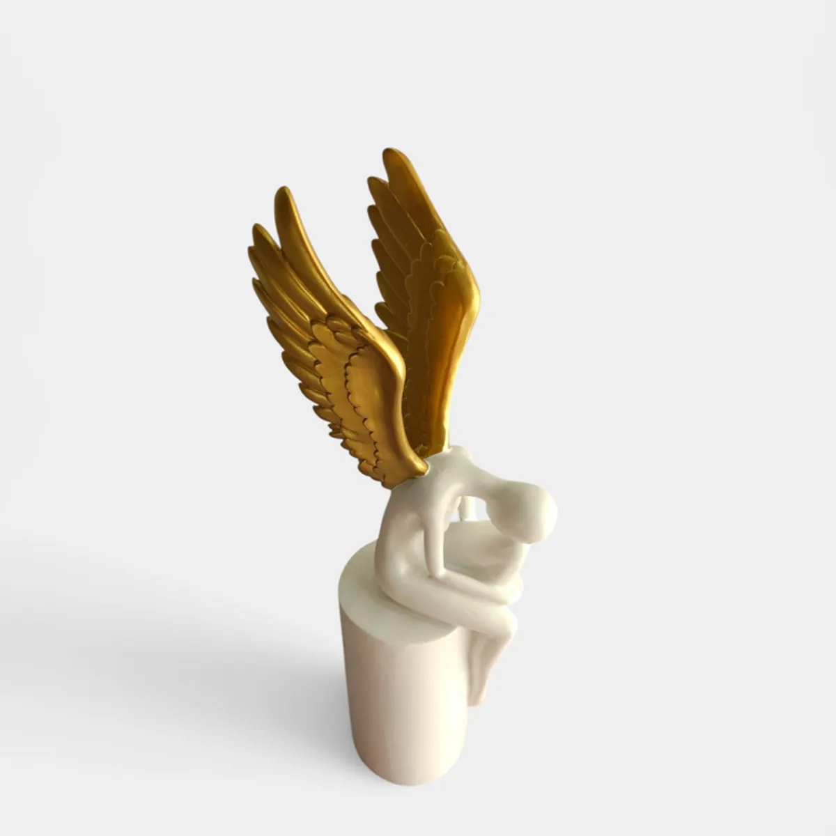 Top view of a white and gold abstract winged figurine with a seated form