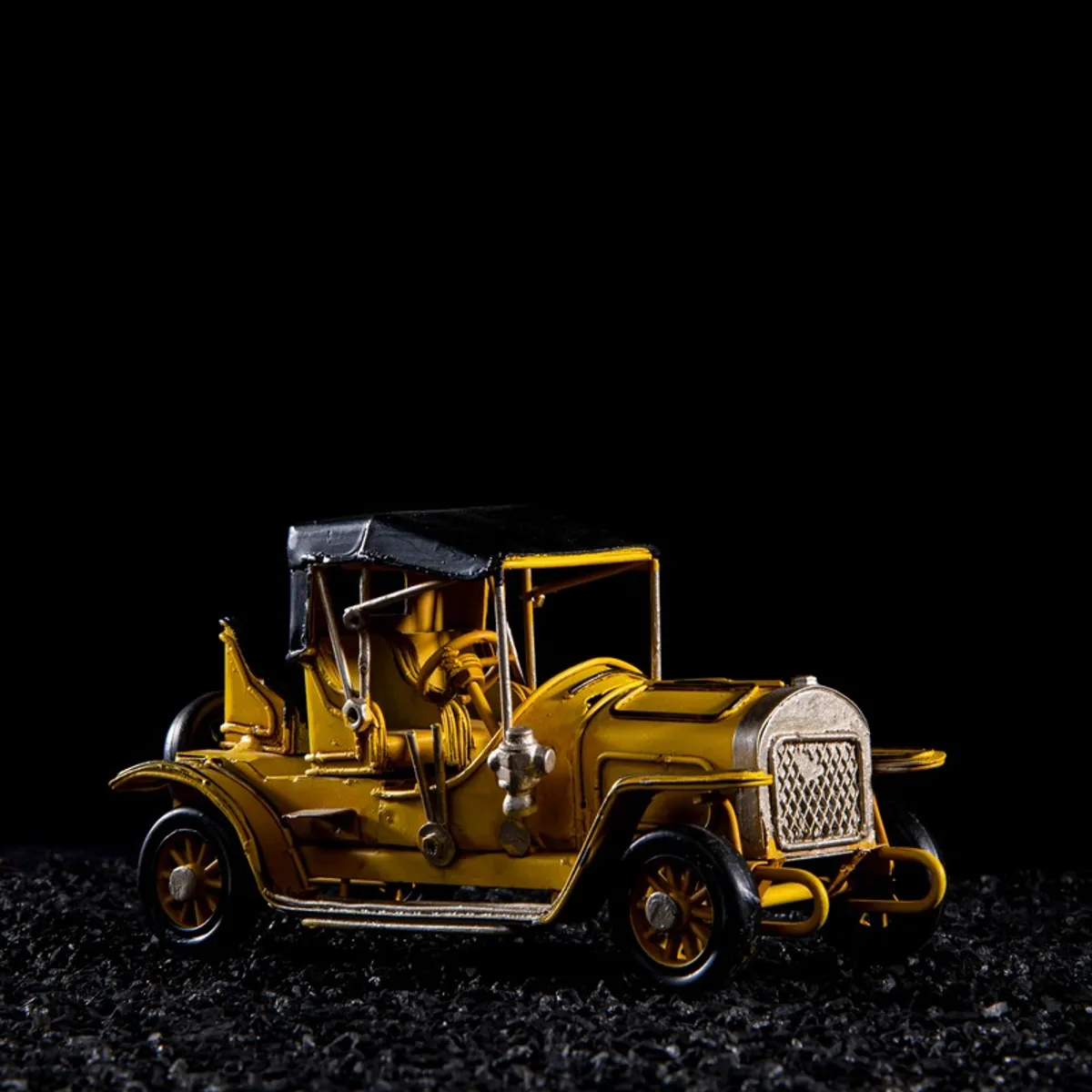 Yellow vintage car showpiece with black roof on a dark background