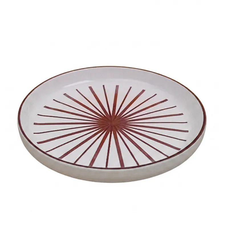Single white snack plate with maroon starburst motif in angled view