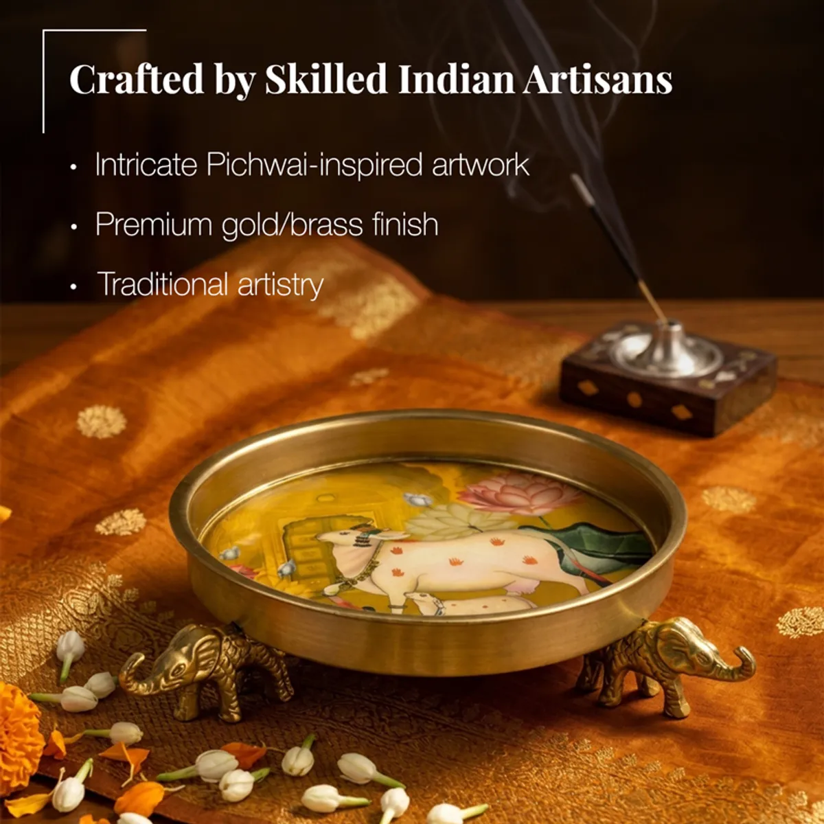 Gold Urli with cow and lotus artwork on an orange textile backdrop
