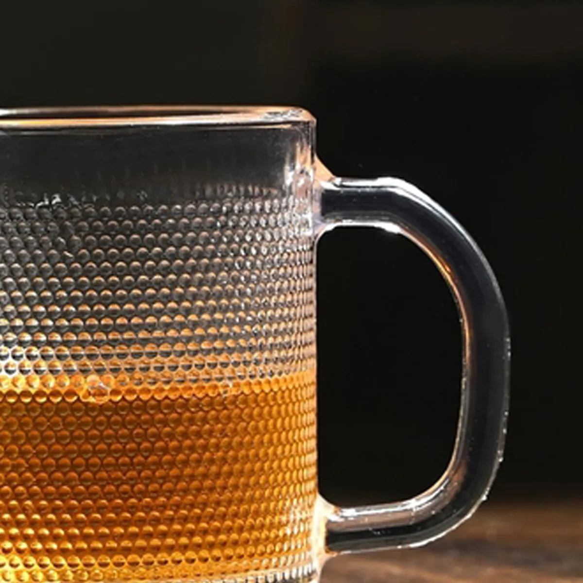 Close-up of a transparent textured glass mug with a clear handle and tea