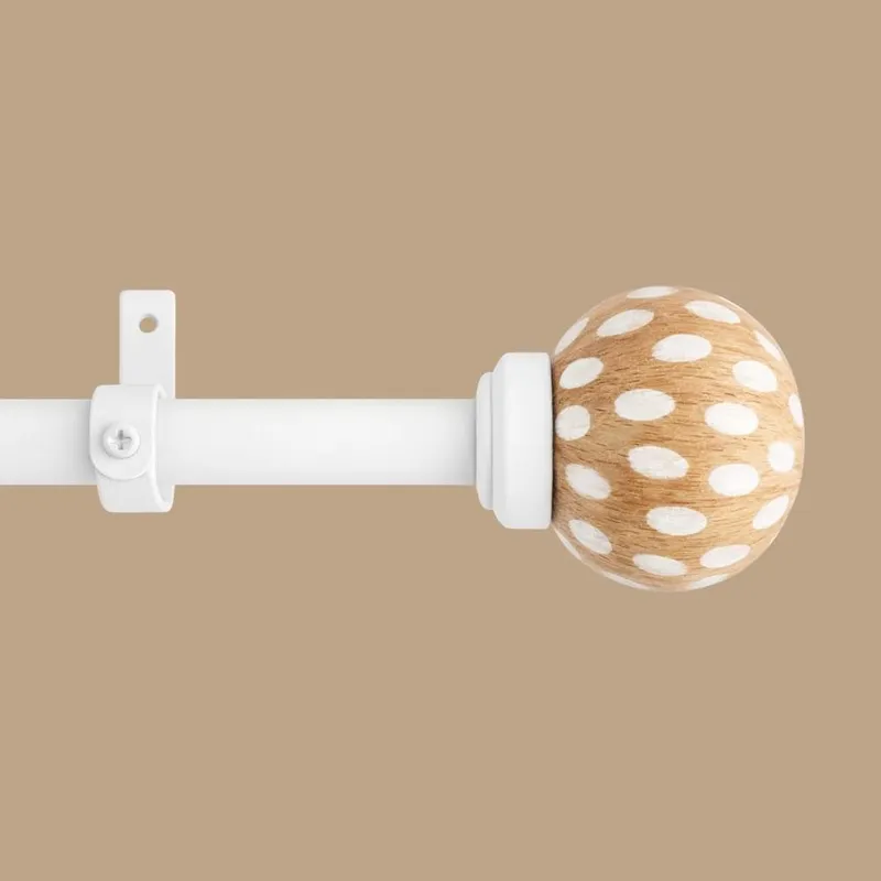 Close-up of white curtain rod with round brown finial and white polka dots