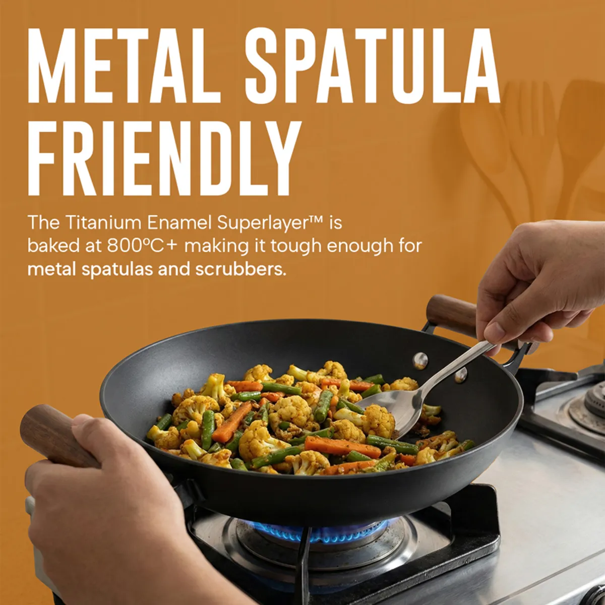 Black kadhai with vegetables on a gas cooktop and metal spatula