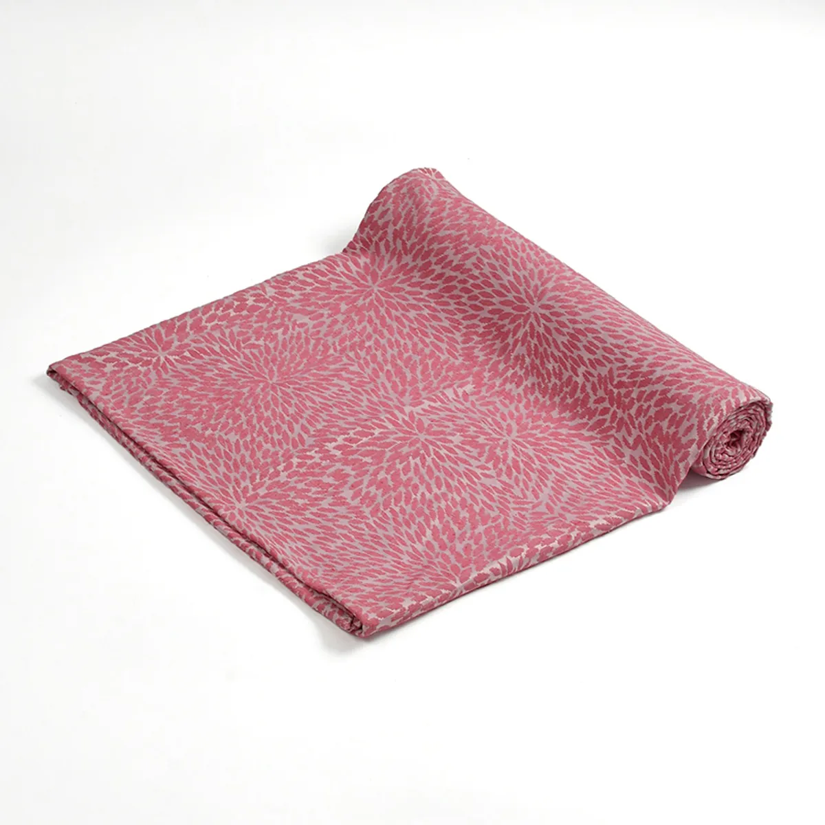 Rolled pink woven throw with all-over floral-inspired pattern on a white background