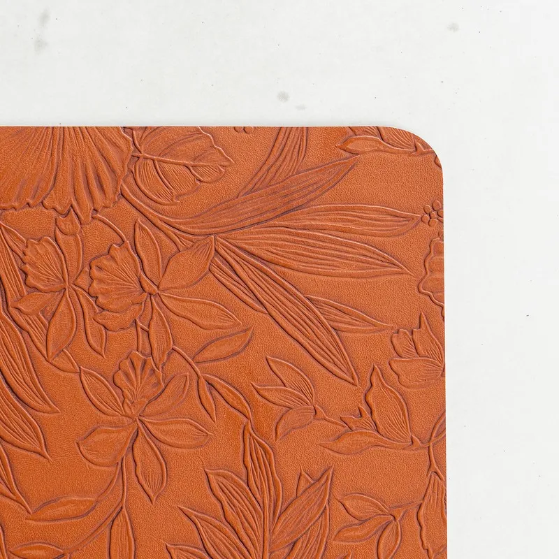 Close-up of orange table mat with embossed floral texture