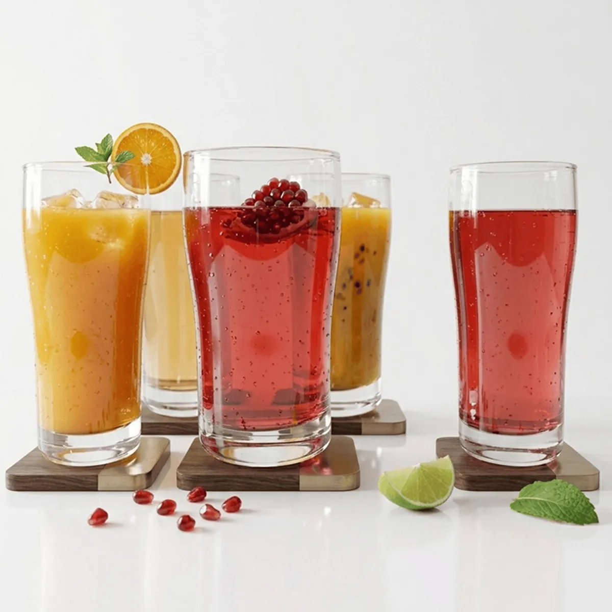 Clear drinking glasses filled with colourful juices and garnished with fruit and mint