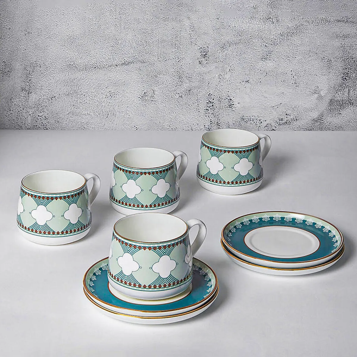 Teal and white patterned cup and saucer set styled with macarons on a marble table