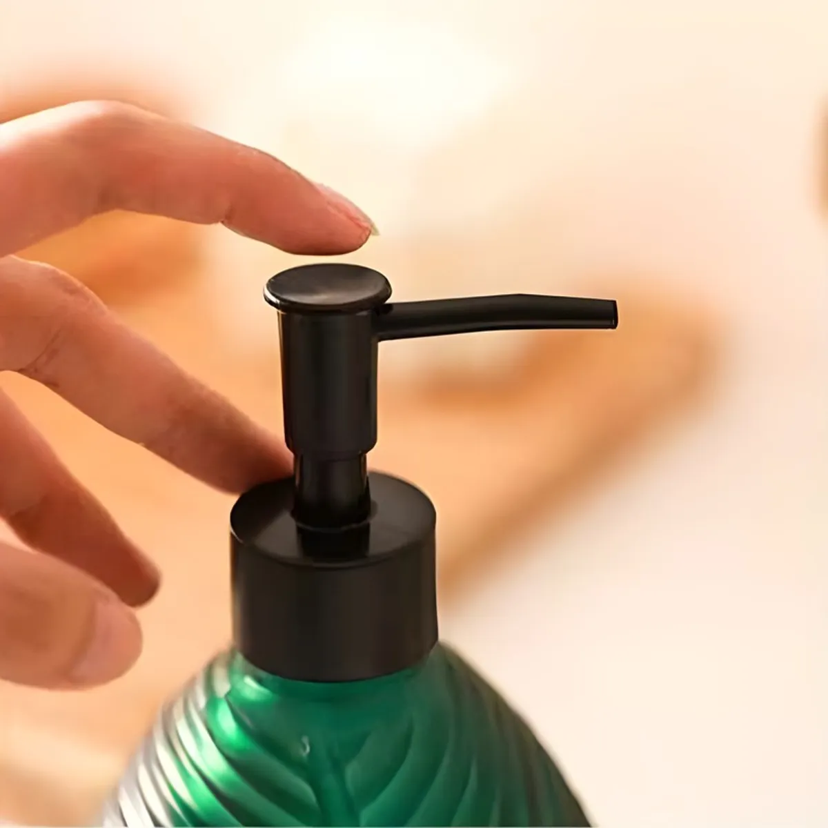 Close-up of a hand pressing the black pump on the green dispenser