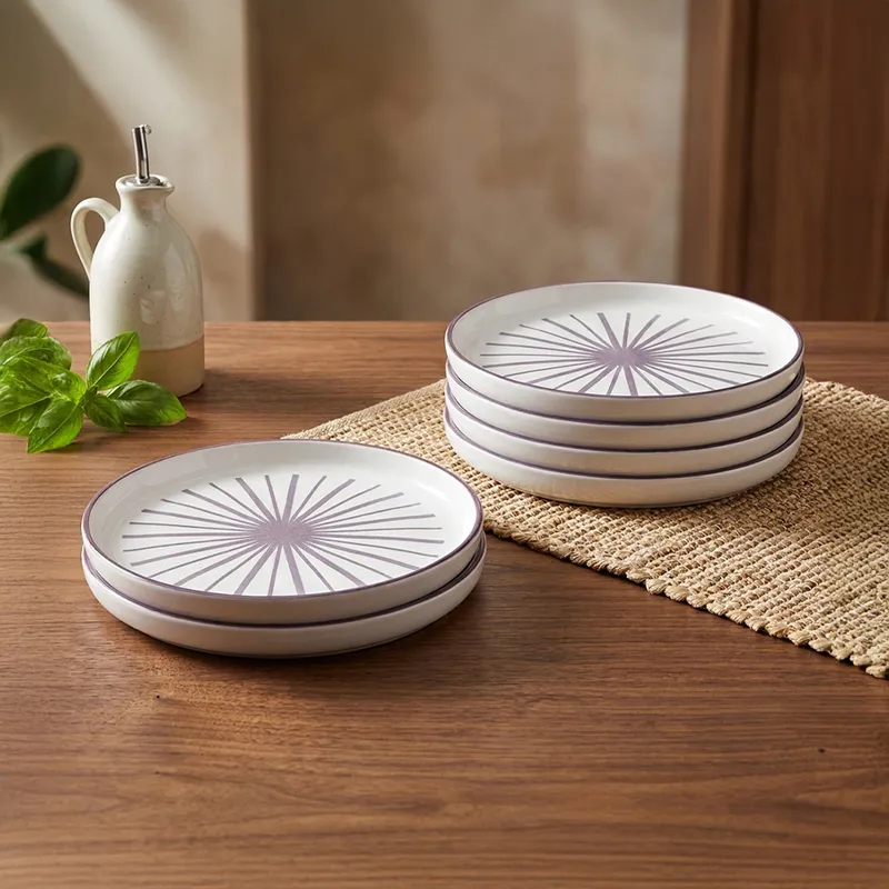 Stacked white and purple snack plates on a wooden dining table